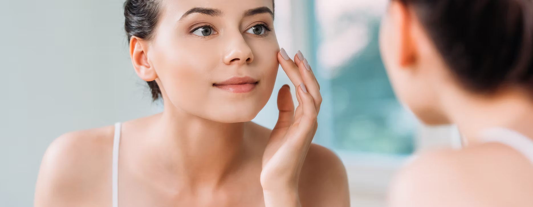 Woman looking at her skin in a mirror.